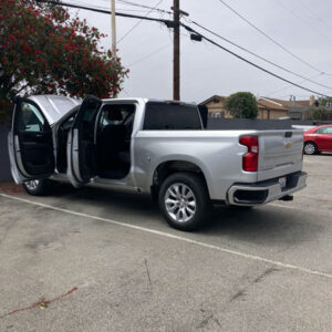 A silver 2024 Chevy Silverado undergoing professional cigarette smoke removal treatment at a dealership in Huntington Beach.