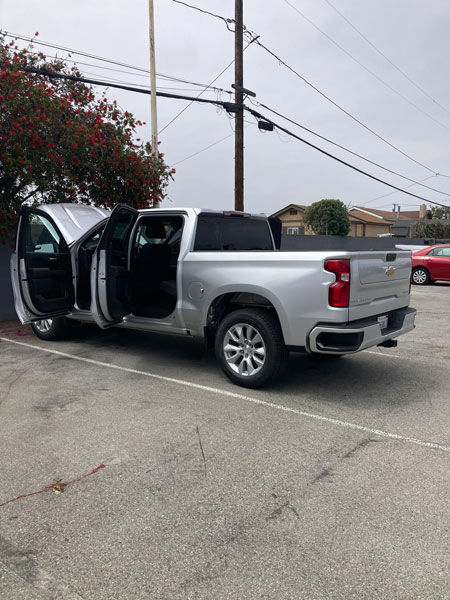 A silver 2024 Chevy Silverado undergoing professional cigarette smoke removal treatment at a dealership in Huntington Beach.